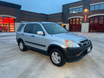 2002 Honda CR-V in silver color, manual AWD with 149K miles, parked in front of a building.
