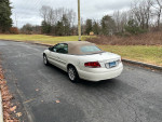 2006 Chrysler Sebring Touring FWD parked on a road with trees in the background, showing its stylish design.