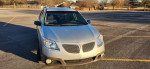 2006 Pontiac Vibe in silver with low mileage, parked in an empty lot showcasing its reliable design.