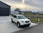 2010 GMC Acadia SLT in pearl white, parked in front of a garage, showcasing its sleek design and dual roofs.