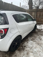 2016 Chevrolet Sonic LT hatchback in white with black rims parked in snowy yard