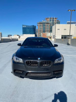 Front view of a sleek 2014 BMW M5 parked in an urban setting, showcasing its luxury design.