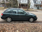 2004 Subaru Impreza station wagon in green, parked on a residential street with leaf-covered ground