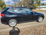 Side view of a 2015 BMW X1 AWD in black, showcasing sleek design and alloy wheels.