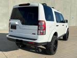 White 2013 Land Rover LR4 HSE Luxury with off-road wheels parked, showcasing its sleek design in excellent condition.