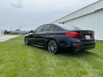 2017 BMW 540i xDrive M Sport parked on grass, showcasing sleek design and polished wheels.