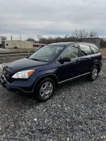 2009 Honda CR-V in dark blue color, parked outside on gravel, showcasing its clean exterior and all-wheel drive features.