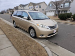 2011 Toyota Sienna XLE van parked on the street, showcasing its beige color and clean exterior.