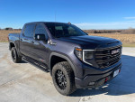2022 GMC Sierra 1500 AT4X 4WD in gray with off-road tires parked in a rural setting