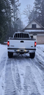 Rear view of a lifted 2001 Ford F350 crew cab truck in snowy surroundings.