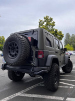 2015 Jeep Wrangler Rubicon in Tank Green with AEV accessories parked in a lot.