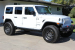 2018 Jeep Wrangler Sahara with aftermarket wheels and lift kit, parked in driveway