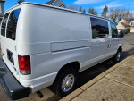 2012 Ford E-250 work van with storage cabinets, well-maintained and in good condition, parked on a driveway.