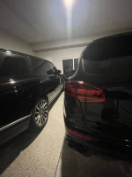Two luxury black cars parked inside a garage, showcasing a Land Rover Range Rover beside another vehicle.