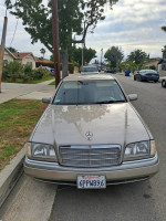 Front view of a well-maintained Mercedes-Benz C280 in a residential area with clean exterior and original leather interior.
