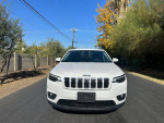 Front view of a white 2019 Jeep Cherokee Latitude FWD parked on a street with trees.
