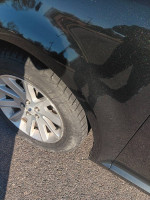 Close-up of the tire and black metallic exterior of a 2013 Ford Escape SEL with small dent.