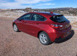 2018 Chevrolet Cruze hatchback in excellent condition parked on a gravel road with scenic landscape.