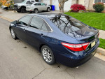 2015 Toyota Camry XLE in blue parked on the street, showcasing its clean design and sleek profile.