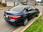 2015 Toyota Camry XLE in dark blue parked on a residential street, showcasing its sleek design and excellent condition.
