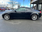 2005 Infiniti G35 Coupe with aftermarket rims, sleek black exterior, parked on the street with clear sky.