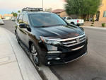 2017 Honda Pilot Elite AWD parked on the street, showcasing its sleek black exterior and stylish wheels.