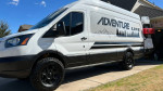 2017 Ford Transit 250 motovan with off-road tires, custom build and electric features, parked at home.