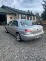 Well maintained Subaru Impreza with body damage parked outside a house, ready for repair or project.