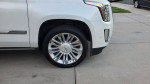 Close-up of the wheel and side view of a 2017 Cadillac Escalade Platinum in diamond white color.