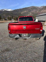 Rear view of a 2012 Ram 2500 Power Wagon in red, parked on a gravel road with mountains in the background.