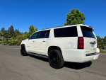 2015 Chevrolet Suburban LTZ in off-white paint with black wheels, parked in a sunny outdoor setting.