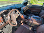 Interior of a 2015 Chevrolet Suburban LTZ with caramel leather seats and high-tech dashboard features.