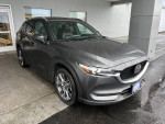 2019 Mazda CX-5 Signature in gray parked under a covered area, showcasing its sleek design and modern features.