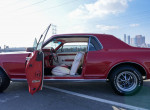 Classic 1968 Mercury Cougar with a vibrant red exterior and white interior, doors open, parked in Los Angeles.