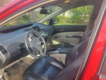 Interior view of a 2006 red Toyota Prius with black leather seats and dashboard features.