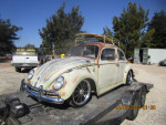 1963 VW Bug with vintage patina paint job on a trailer in a rustic setting