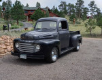 1950 Ford F1 pickup truck with a flat head V8, new interior, and chrome wheels in a scenic outdoor setting.
