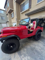 1973 red Jeep CJ5 with new wheels, tires, and interior in a driveway setting