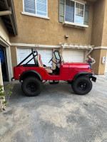 1973 Jeep CJ5 for sale, red with new tires and partially restored, parked in a driveway