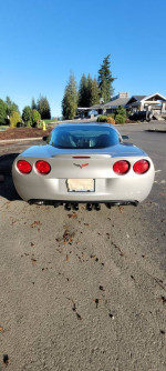 Rear view of a 2005 Chevrolet Corvette with silver metallic finish parked on a sunny day.