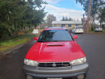 Front view of a 1999 Subaru Outback in great condition, featuring a red exterior and sunroofs.