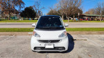 Front view of a 2015 Smart Fortwo Electric Drive in a park setting, showcasing its compact design.