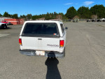 Rear view of a 1998 Mazda B2300 pickup truck parked outdoors, displaying a clean title and needing repairs.