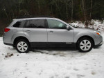 2010 Subaru Outback in silver parked on snow, showing side view with premium features and clean condition.