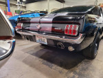 1965 Ford Mustang 2+2 Fastback, Raven Black with charcoal stripes, showcasing a sleek rear view.