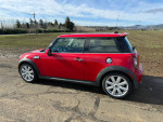 2010 Mini Cooper S in red parked on dirt road, featuring clean design and panoramic sunroof.