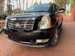 Black Cadillac Escalade with low mileage, showing front view and details like chrome grille and polished headlights.