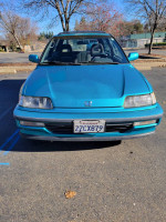 Front view of a 1991 Honda Civic Si in teal color, parked outdoors, showing the car's original condition.