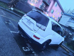 2010 Mitsubishi Outlander in white parked on the street, equipped with winter tires, featuring a spacious interior for 7 passengers.