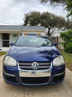 Front view of a 2006 Volkswagen Jetta TDI in Shadow Blue with chrome grille, parked outside a house.